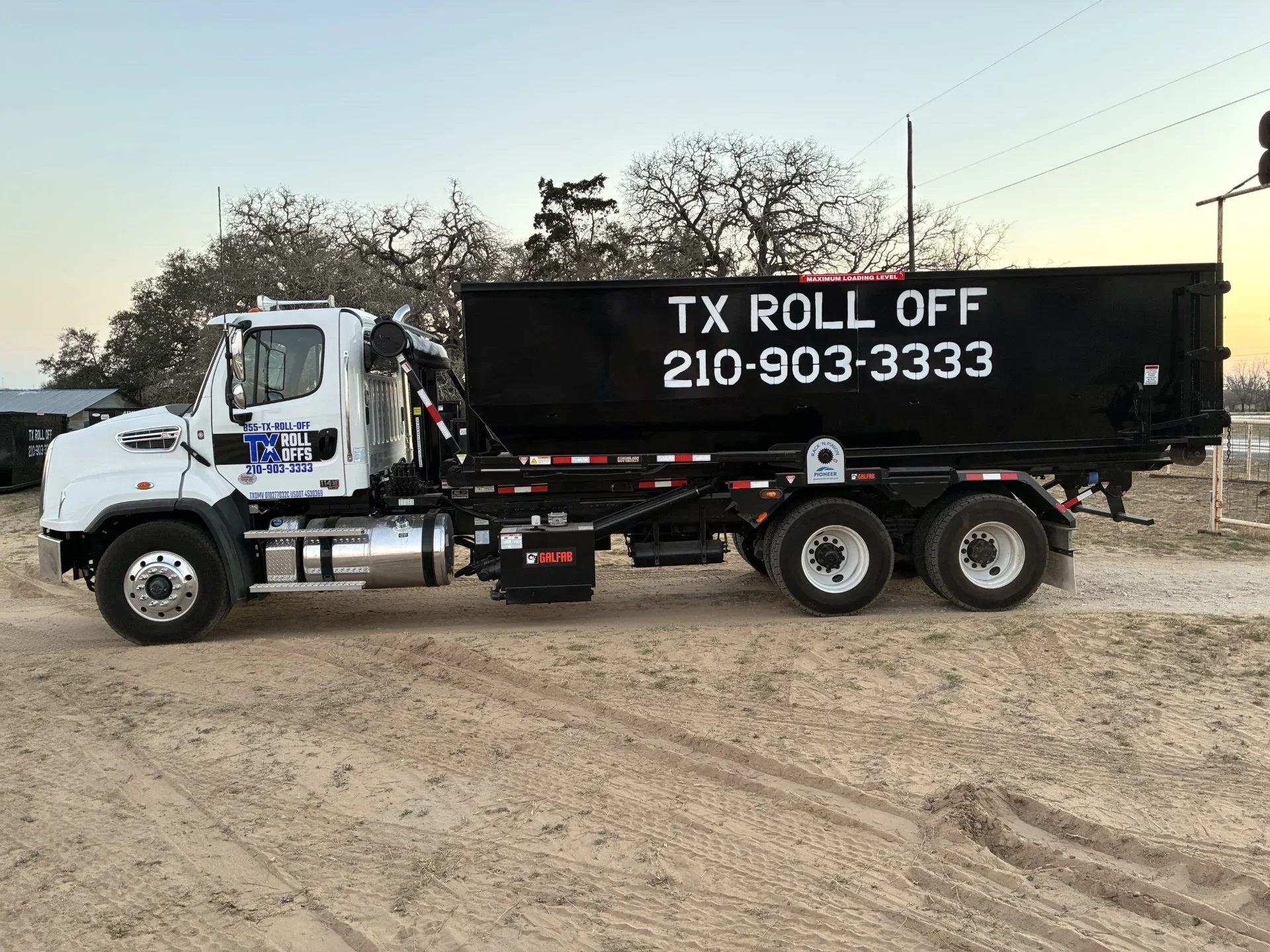 White Isuzu roll-off dumpster truck with black steel container and hydraulic lift system