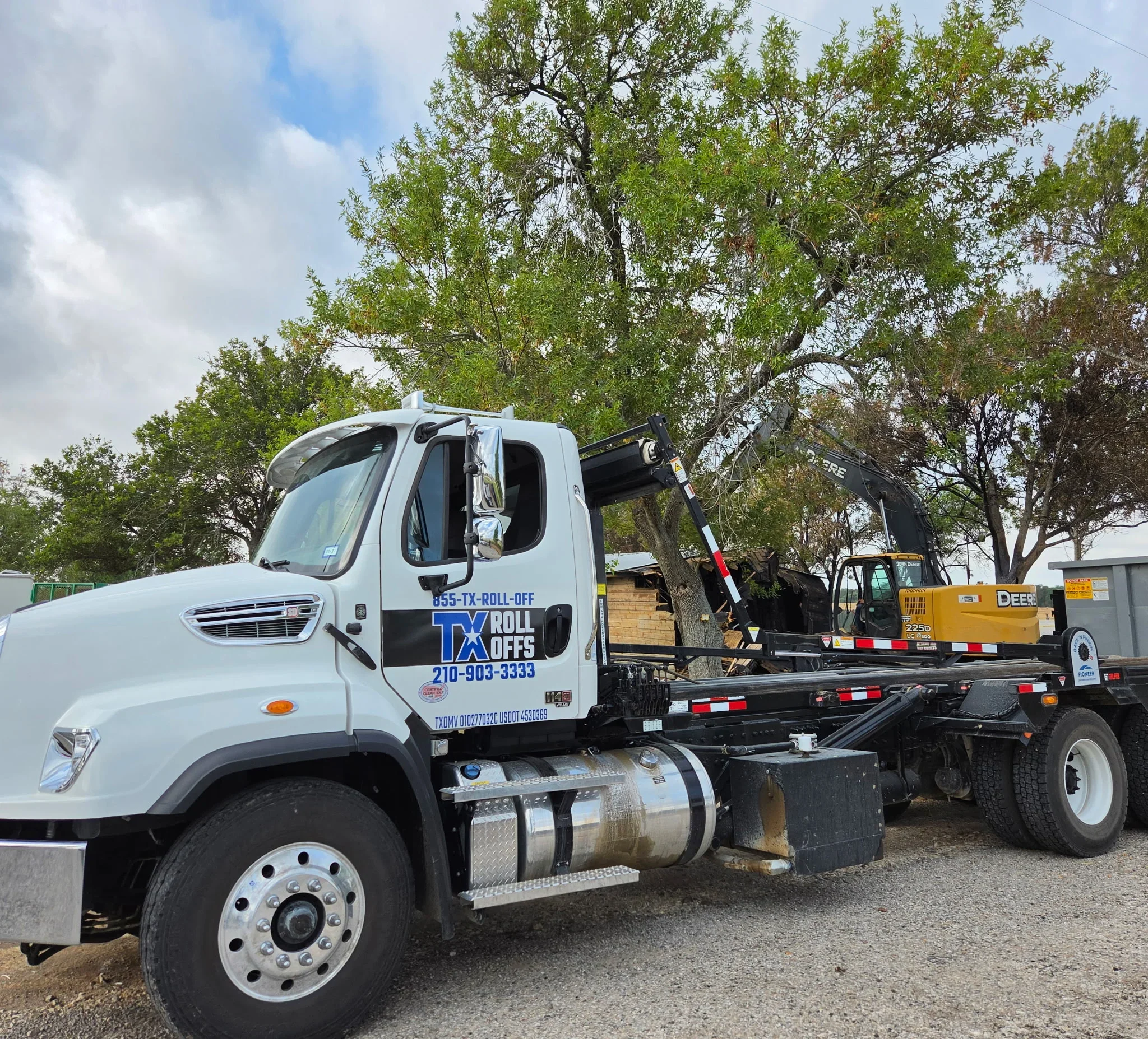 White roll-off dumpster truck with hydraulic arm lowering container at residential site